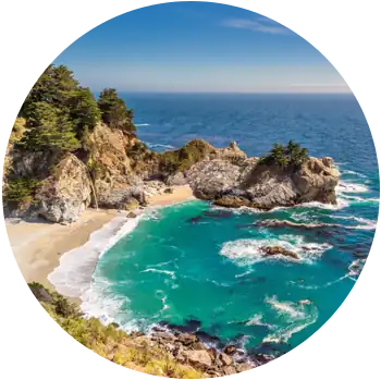 Waves flow out from an enclave surrounded by rock formations at Julia Pfeiffer Beach in the daytime.